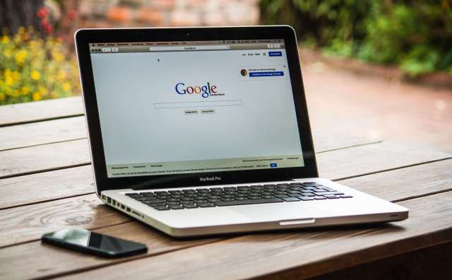 MacBook Pro on a picnic table with the Google homepage opened in a web browser