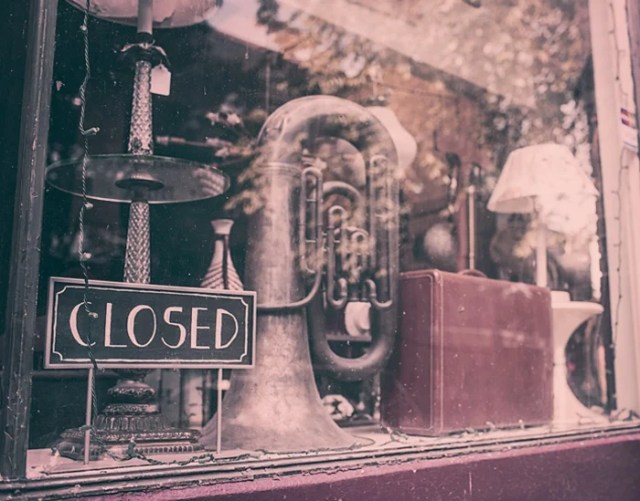 An image of a retail store window with a closed sign An image of a retail store window with a closed sign