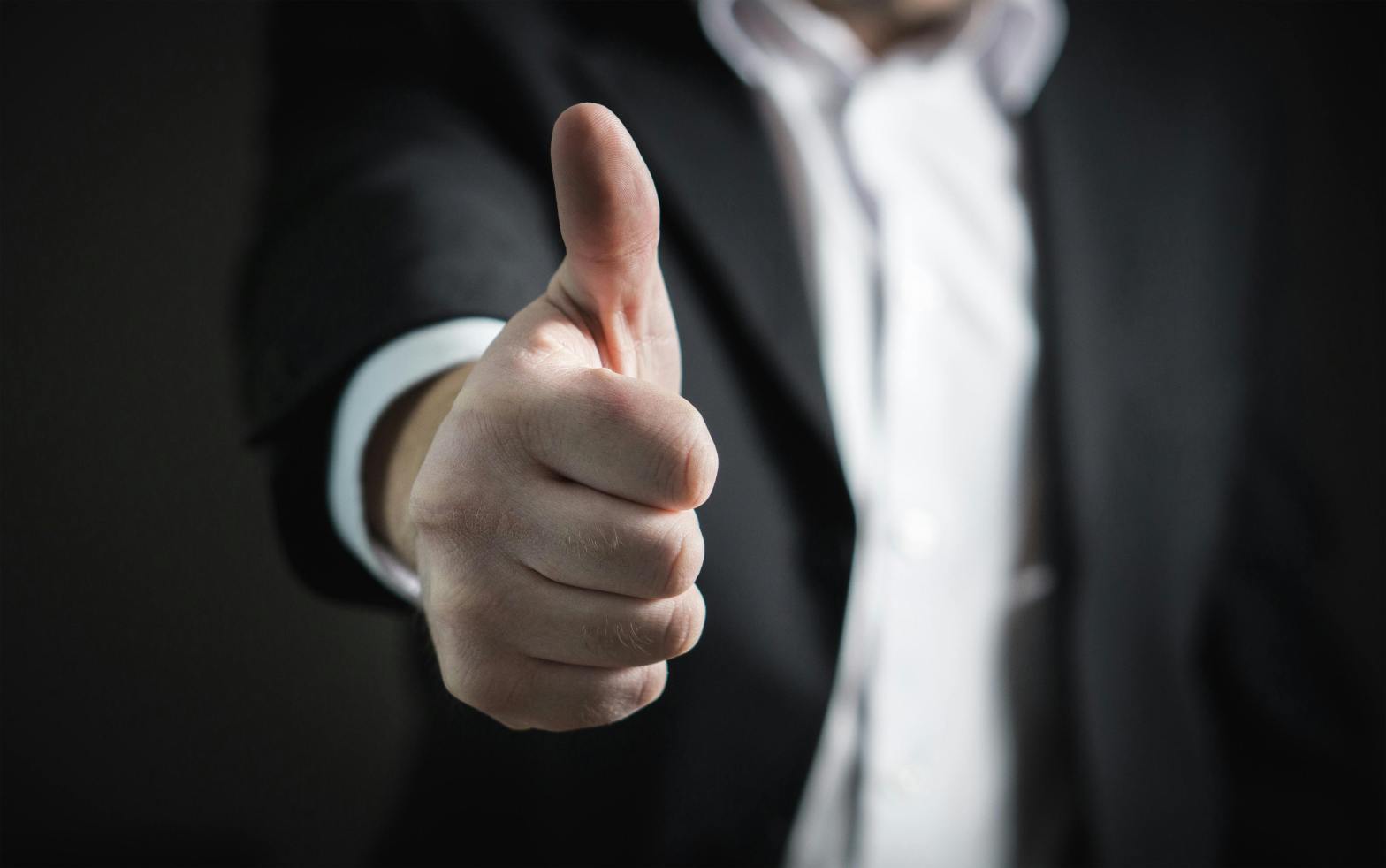 Person wearing suit giving thumbs up signal
