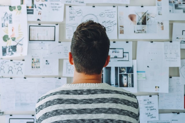 Man looking at a whiteboard filled with papers depicting a content strategy session Man looking at a whiteboard filled with papers depicting a content strategy session