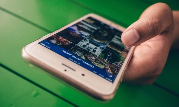 Image of a hand holding a smartphone with a photo gallery to represent using visuals in your blog posts.